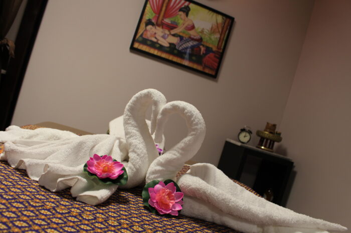 Zwanen van handdoeken met lotusbloemen op een massagebed