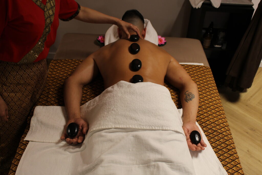Hotstonemassage met warme stenen langs de wervelkolom en in de handen